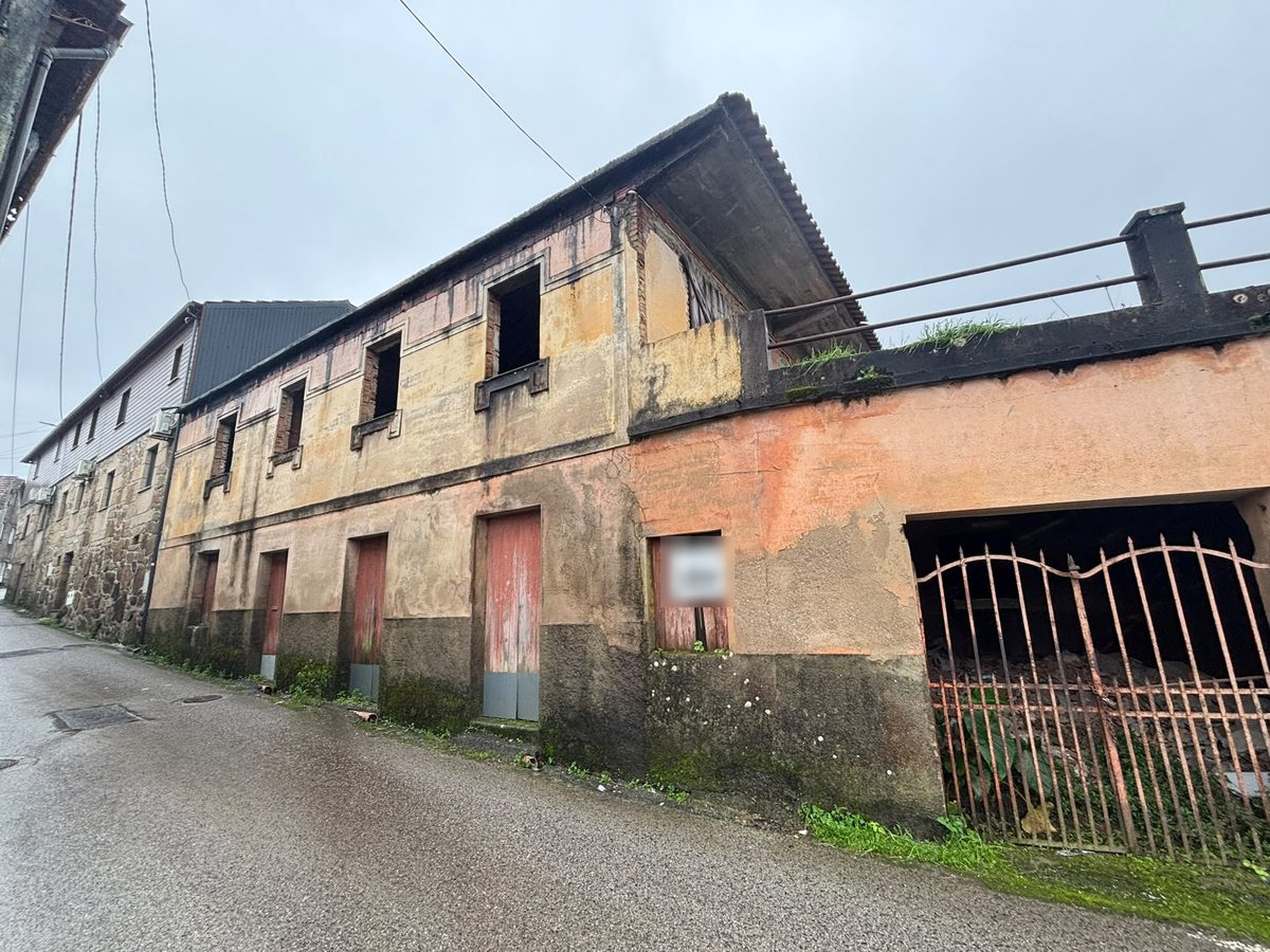 Antes: casa de dois pisos com a fachada gasta e o portão de ferro ao lado
