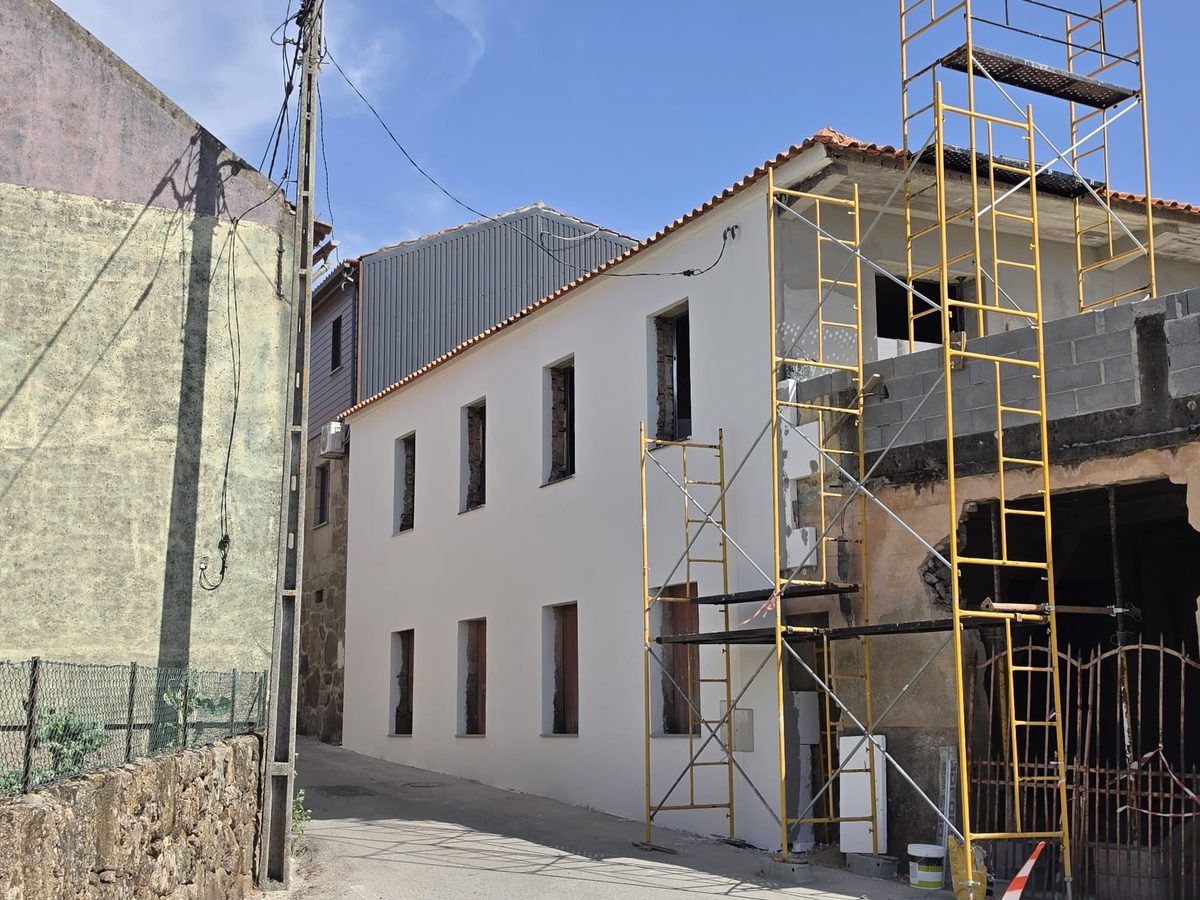 Depois: a mesma casa com a fachada isolada e pintada de branco, ainda com os andaimes