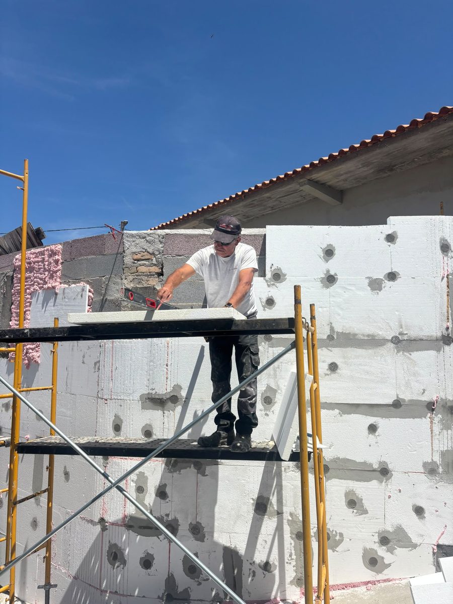 Elemento da equipa no andaime a colocar placas de isolamento na fachada
